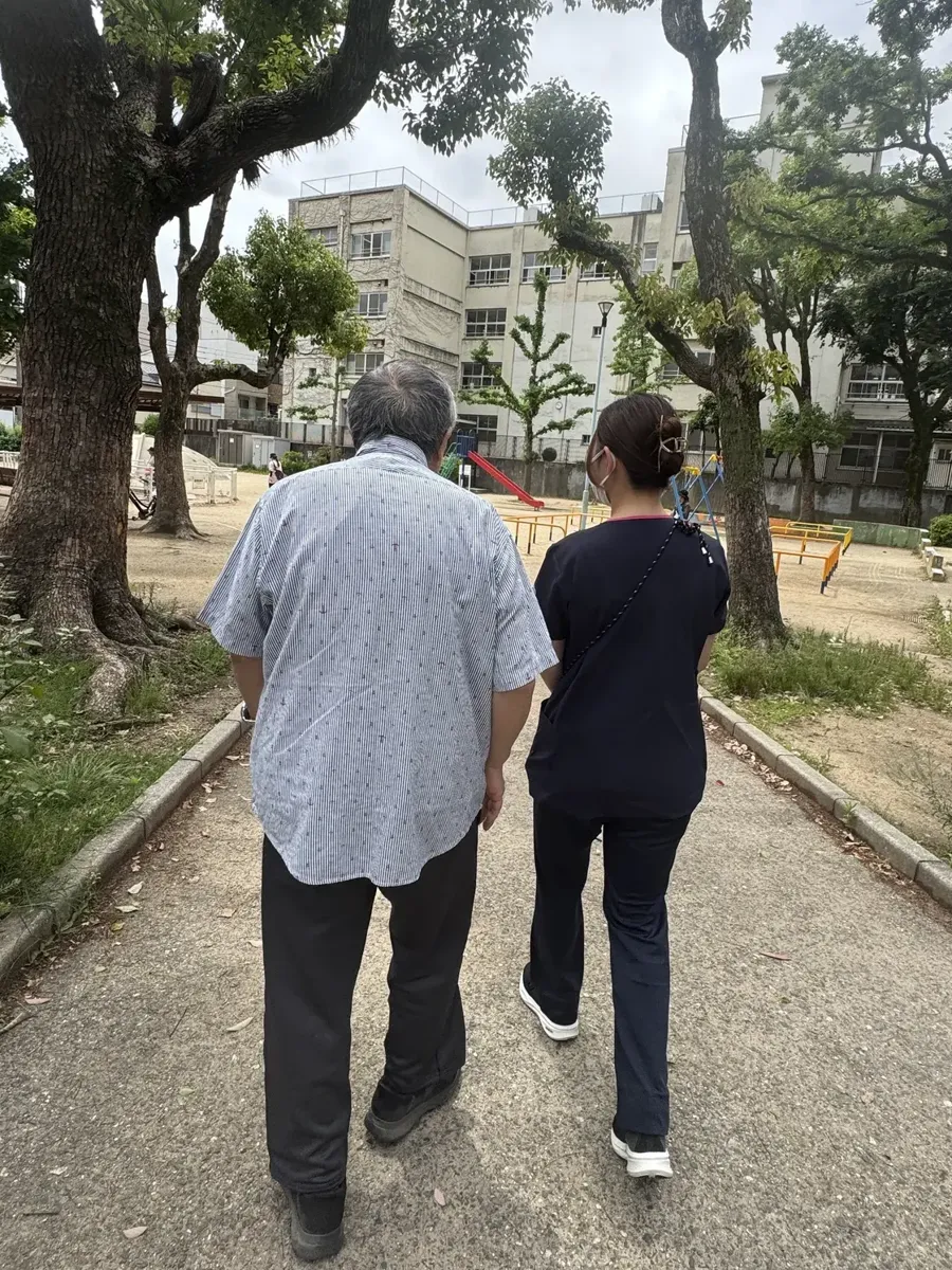 公園の道を、利用者さんと並んで歩く看護師